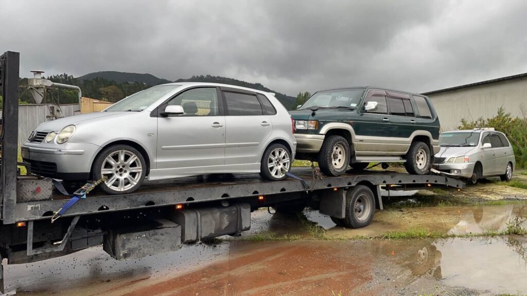 Tow truck transporting two unwanted scrap cars in Christchurch.