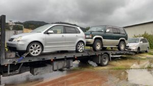 Tow truck transporting two unwanted scrap cars in Christchurch.