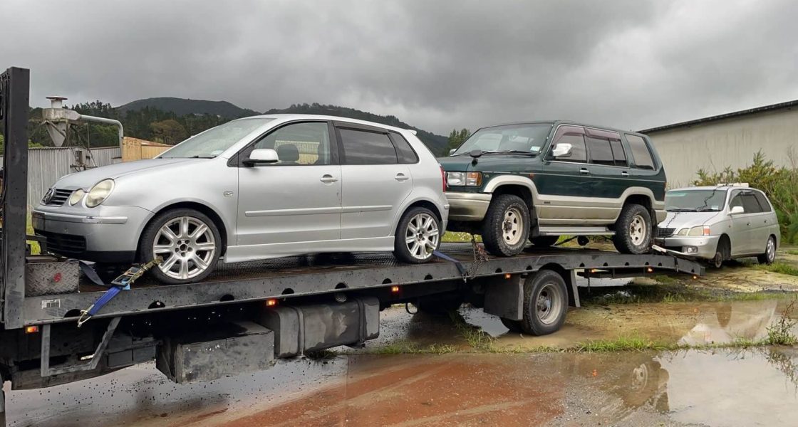 Tow truck transporting two unwanted scrap cars in Christchurch.